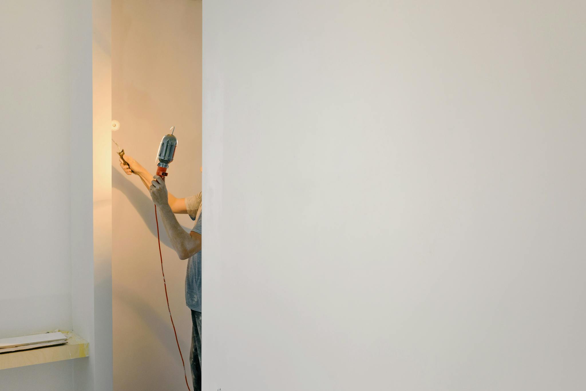 Crop man painting walls in room