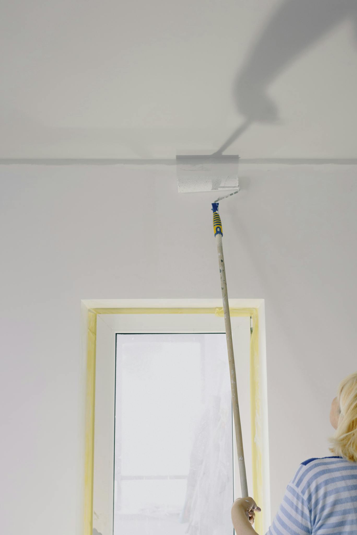 Crop woman painting walls at home